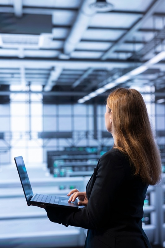 Woman holding a laptop in a data center.