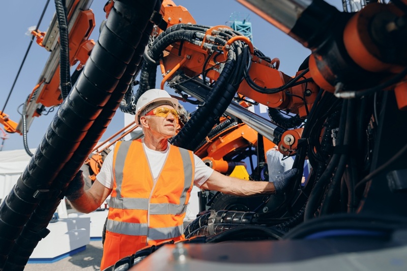 A man checking the system of hydraulic industrial machinery.
